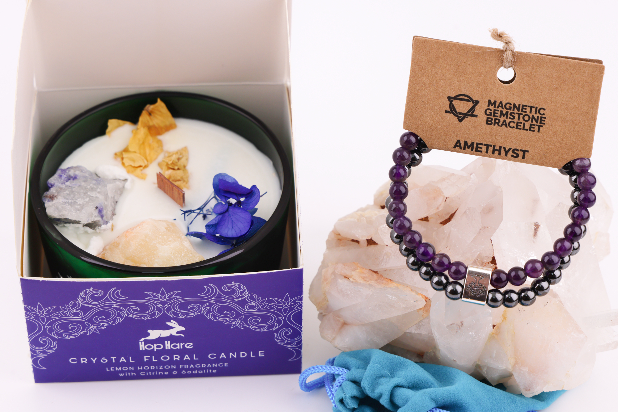 Grüne Hop‑Hare Duftkerze mit Citrin‑ und Amethyst‑Steinen sowie Blüten, daneben die lilafarbene Produktbox; rechts ein Amethyst‑Magnetarmband auf brauner Karte, präsentiert auf Bergkristallen mit türkisfarbenem Beutel.
