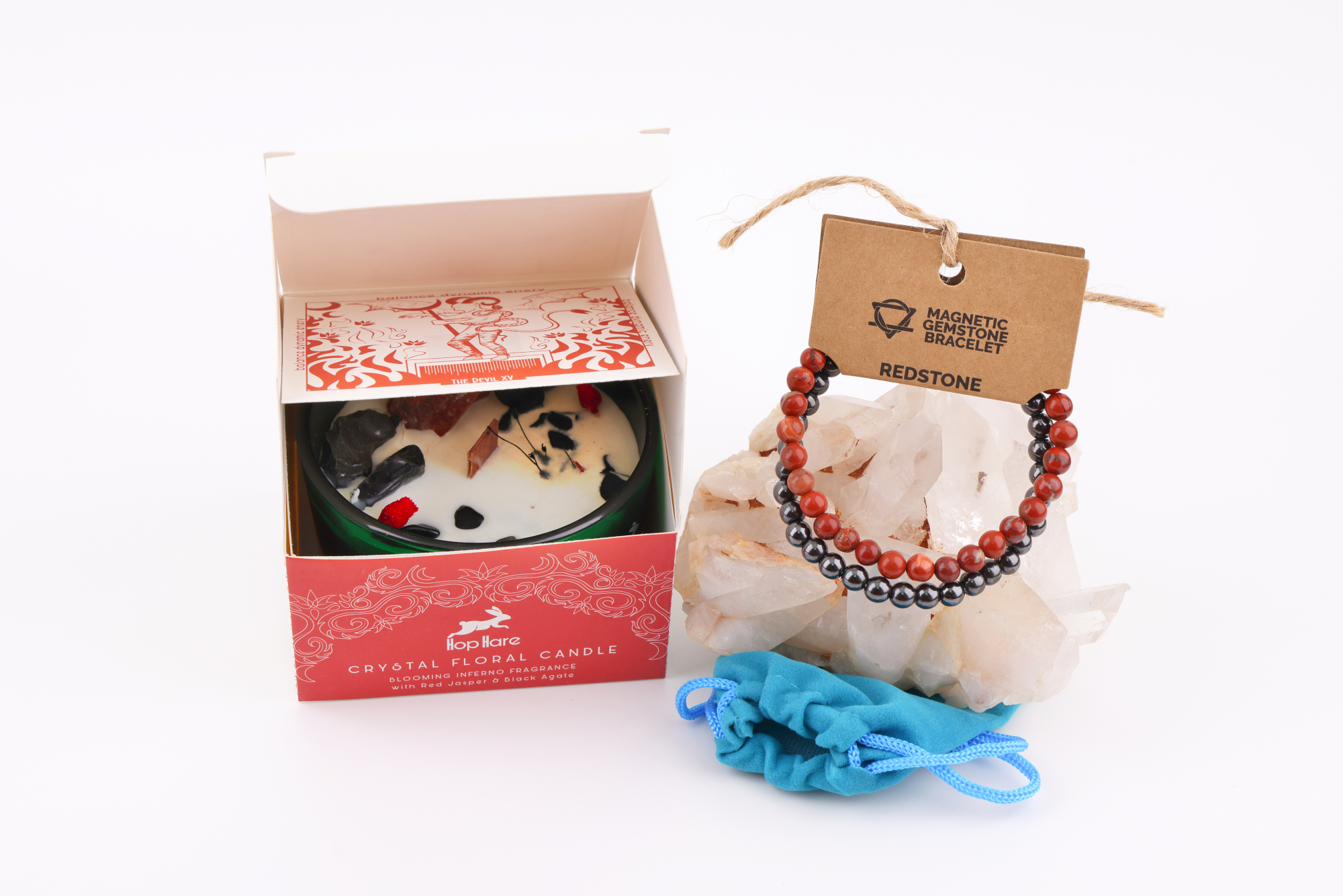 Eine Hop Hare Kerze im Karton mit Kristallen und Blüten, darauf die Tarotkarte „The Devil XV“; daneben ein Redstone‑Magnetarmband auf klaren Bergkristallen und ein kleiner türkisfarbener Stoffbeutel.