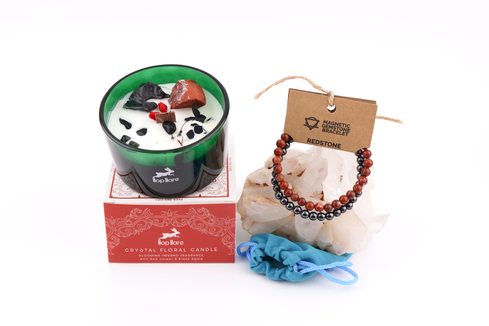 Eine Hop Hare Kerze im Karton mit Kristallen und Blüten, darauf die Tarotkarte „The Devil XV“; daneben ein Redstone‑Magnetarmband auf klaren Bergkristallen und ein kleiner türkisfarbener Stoffbeutel.