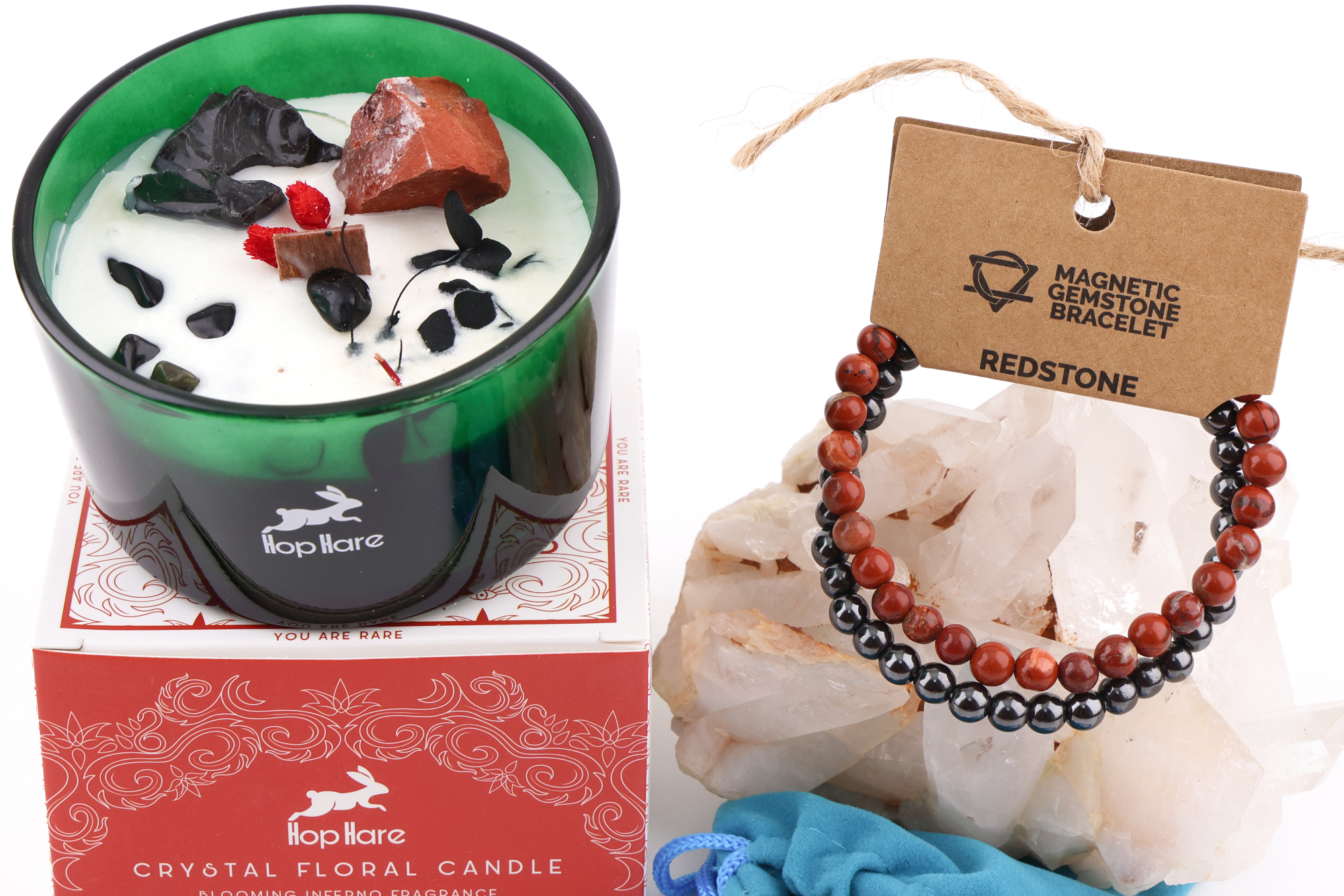 Eine Hop Hare Kerze im Karton mit Kristallen und Blüten, darauf die Tarotkarte „The Devil XV“; daneben ein Redstone‑Magnetarmband auf klaren Bergkristallen und ein kleiner türkisfarbener Stoffbeutel.