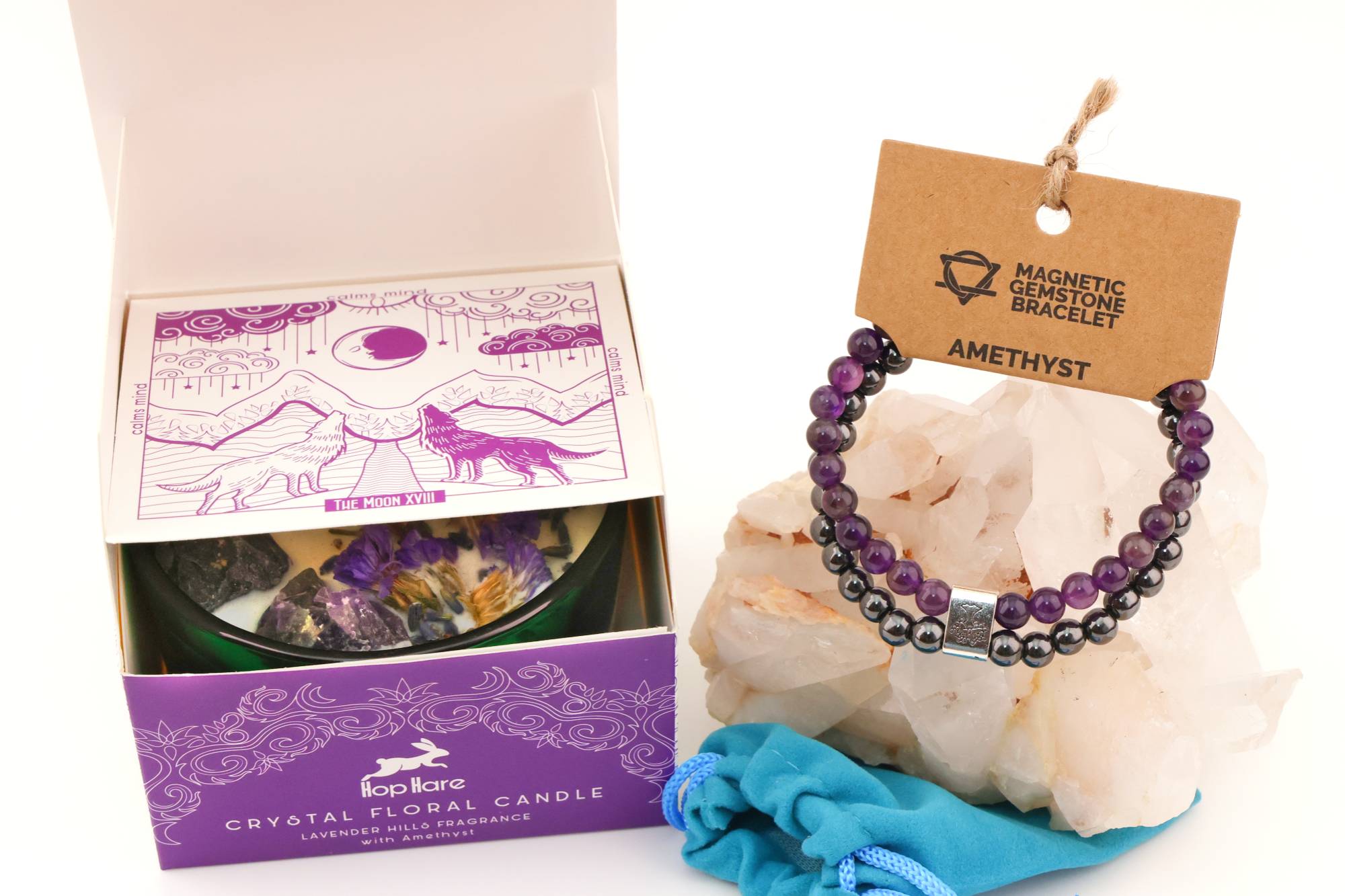 Grüne Hop‑Hare Duftkerze mit Citrin‑ und Amethyst‑Steinen sowie Blüten, daneben die lilafarbene Produktbox; rechts ein Amethyst‑Magnetarmband auf brauner Karte, präsentiert auf Bergkristallen mit türkisfarbenem Beutel.