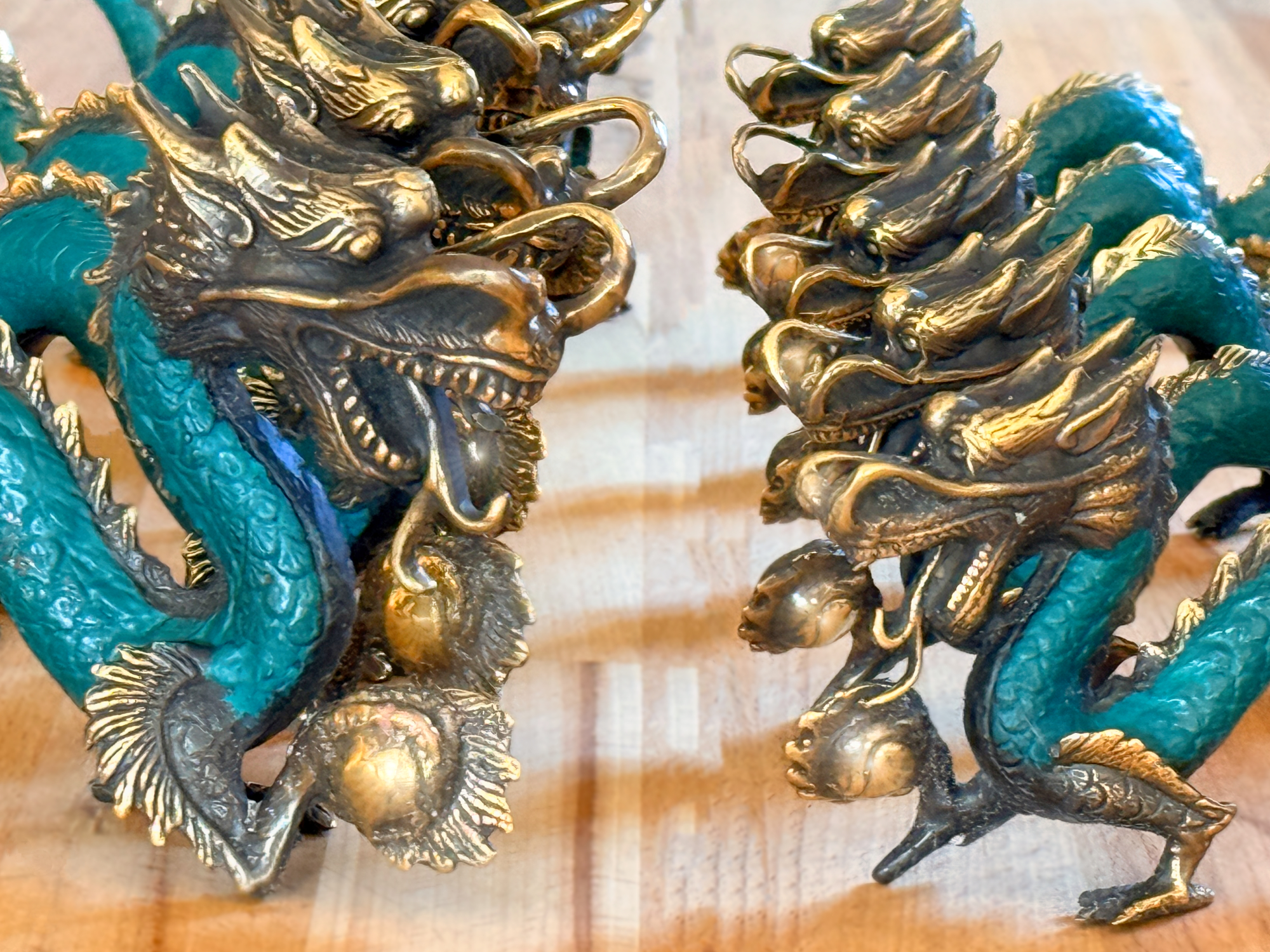 Grün-goldene Messing‑Drachenfiguren mit langem geschwungenem Körper, geöffnetem Maul und goldener Energiekugel in der Klaue.