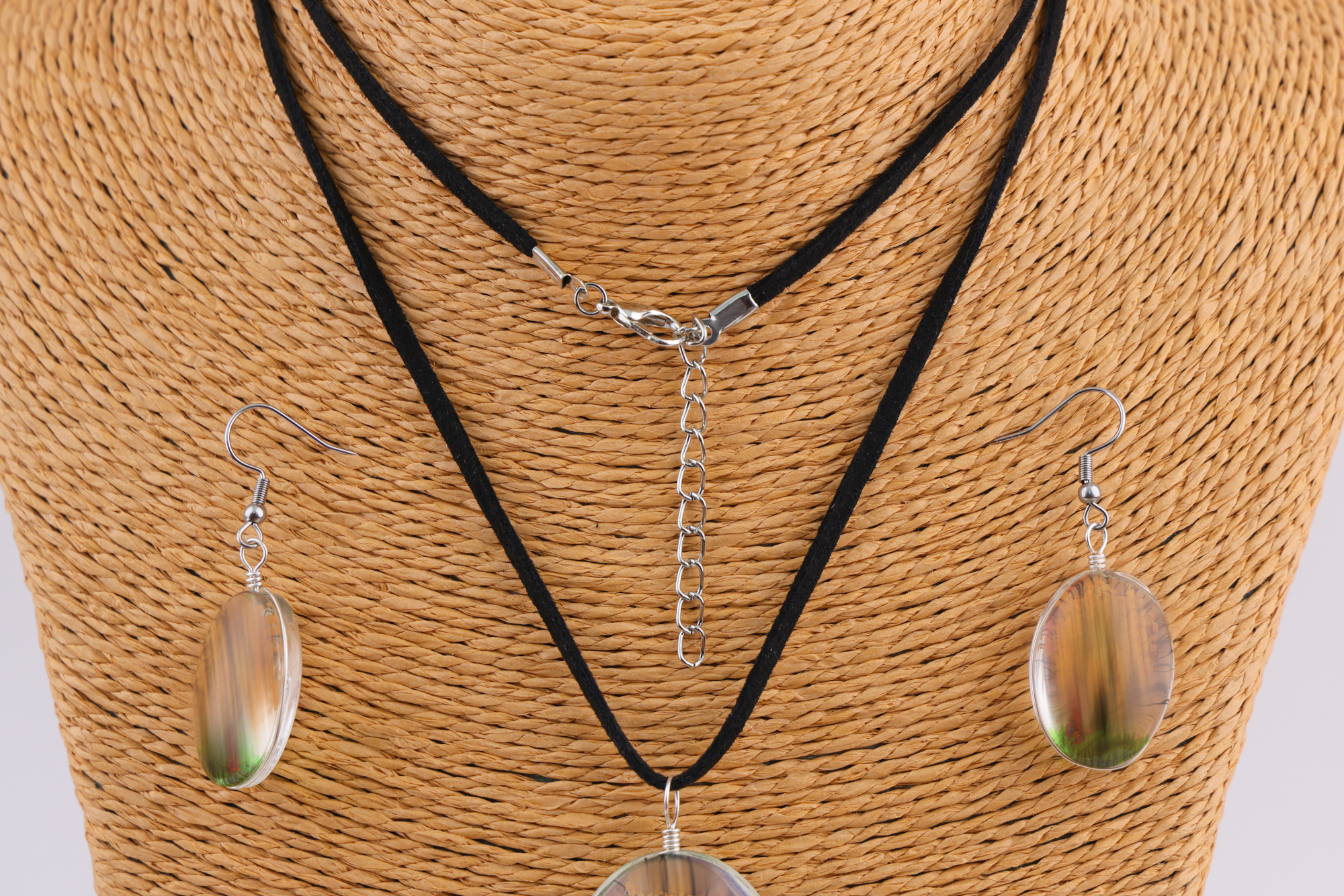 Ovales Schmuckset in Braun‑Gold und Grün auf Schmuckständer.